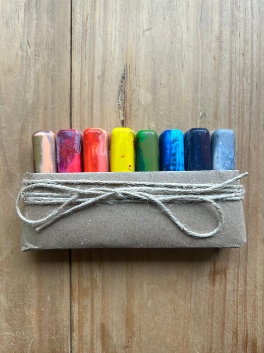 Set of colorful crayons in a cardboard holder on a wooden surface